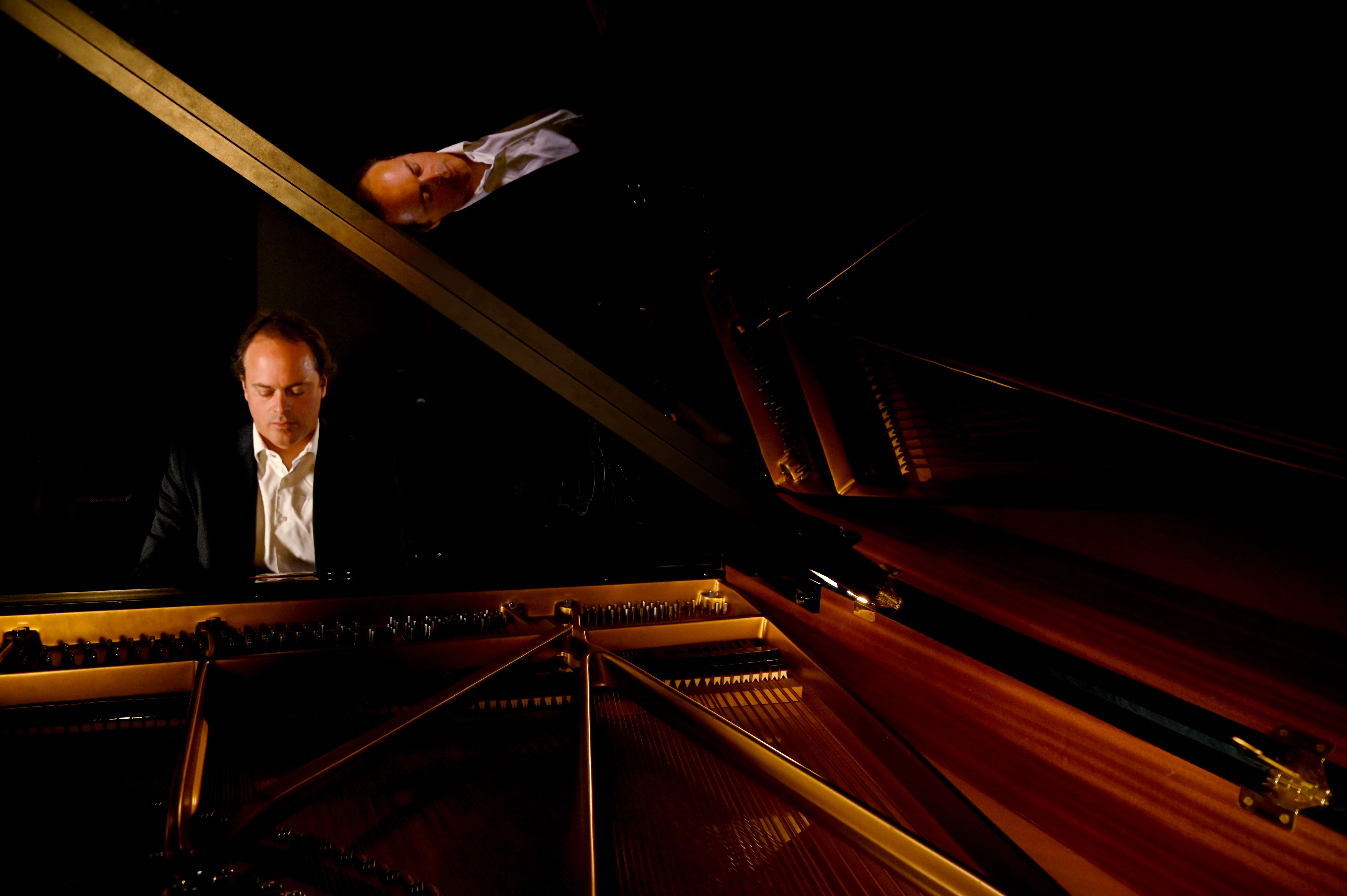 Couvercle ouvert, vue intérieure du piano en bois de noyer, ambiance feutrée.